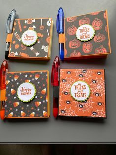 four halloween themed notebooks and pens on a table