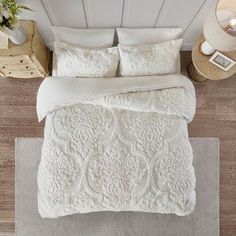 an aerial view of a bed with white comforter and pillows on top of it