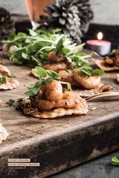 some food is laying out on a wooden table next to a candle and pine cones