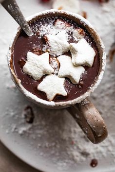 hot chocolate with marshmallows and powdered sugar in a mug on a plate