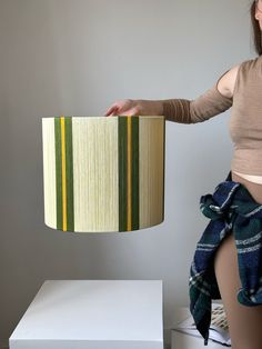 a woman is holding up a lamp shade