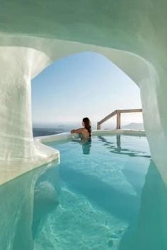 a woman is sitting in the middle of a swimming pool and looking out at the ocean