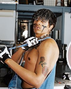 a shirtless man with tattoos holding a baseball bat