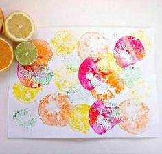 oranges and lemon slices are sitting on a paper with paint splattered over them