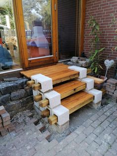 a wooden bench sitting in front of a brick wall next to a building with windows