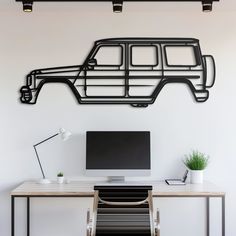 a desk with a computer and chair in front of a wall that has a car on it