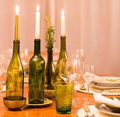 a wooden table topped with wine bottles and glasses filled with wine next to candles on top of it