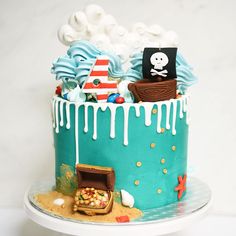 a cake decorated with blue icing, pirate ship and other items on a plate