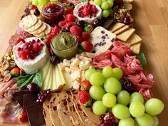 an assortment of cheeses, fruits and meats on a platter