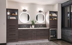 a bathroom with double sinks and two round mirrors on the wall, along with dark wood cabinets