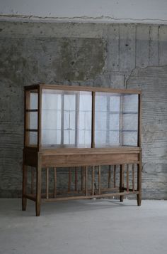 a wooden bench sitting in front of a wall with glass doors on it's sides