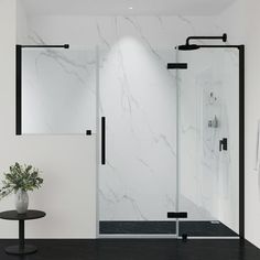 a white bathroom with black accents and marbled walls, including a walk in shower