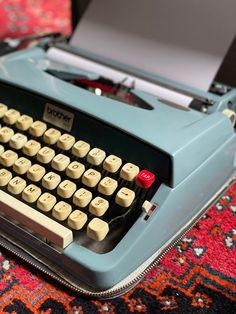 an old fashioned blue typewriter sitting on top of a rug