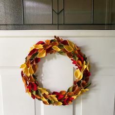 a wreath hanging on the front door of a house decorated with autumn leaves for fall