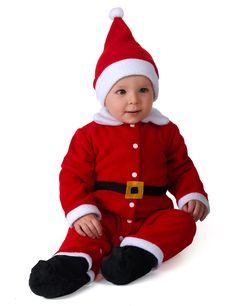 a baby dressed in a santa suit sitting on the floor with his legs crossed and feet crossed