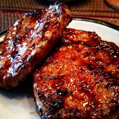 two pieces of meat sitting on top of a white plate