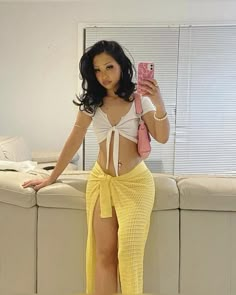 a woman taking a selfie while wearing a yellow skirt and holding a cell phone