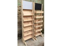 two wooden bookshelves sitting next to each other in front of a stone wall