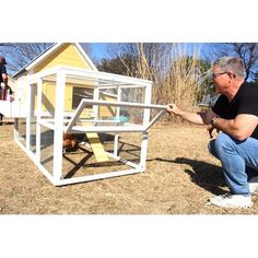 a man kneeling down in front of a chicken coop