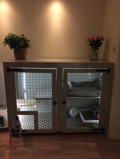 a caged in dog house with flowers on the top shelf and two dogs inside