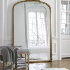 a large mirror sitting on top of a hard wood floor next to a white wall