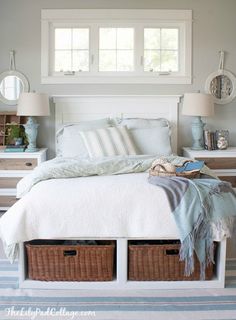 a white bed with two baskets under the headboard and pillows on top of it