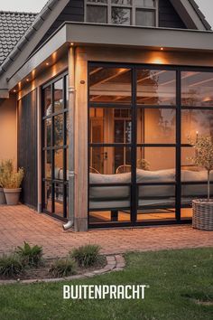 a house with glass doors and lights on the outside, in front of it is a patio