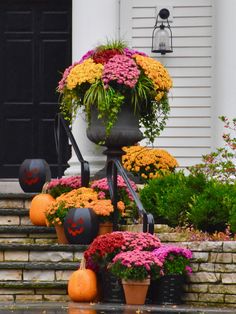 some pumpkins and flowers are sitting on the steps