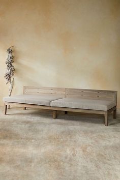 a wooden bench sitting on top of a floor next to a vase filled with flowers