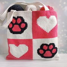 a crocheted bag with hearts and paw prints on it, sitting on a table