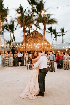 a bride and groom share their first dance at the beach wedding reception in front of a tiki hut