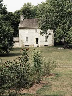 an old white house in the middle of a field