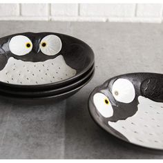 two black and white plates with eyes painted on them, one has an owl face