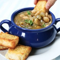 a person dipping some bread into a bowl of soup