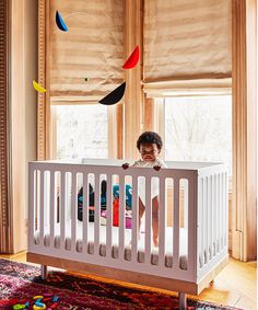 a young child standing in a white crib