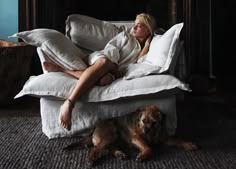 a woman laying on top of a bed next to a dog