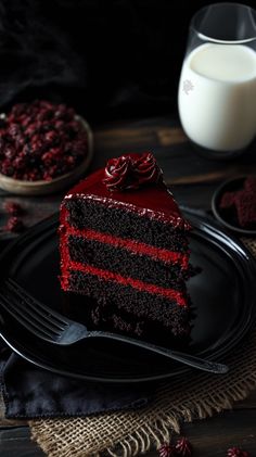 a piece of red velvet cake on a black plate with a fork next to it