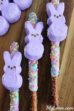 some bunny shaped candy sticks on top of a wooden table with sprinkles