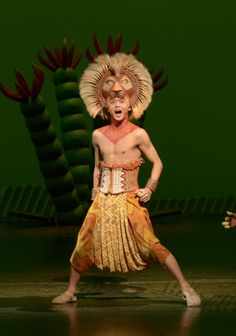 a man in an elaborate costume standing on stage with his mouth open and hands behind him