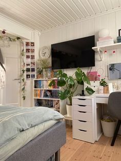 a bedroom with a bed, desk and television on the wall in front of it