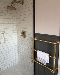 a white tiled shower with gold fixtures and towel racks on the wall next to it