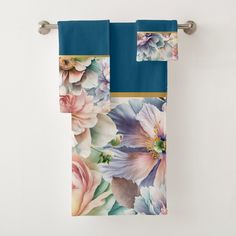 two towels hanging on a towel rack with blue and pink flowers painted on them in front of a white wall