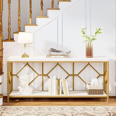 a white and gold console table with books on it in front of some banisters