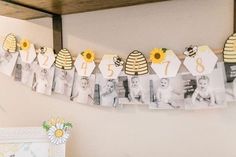 a baby's first birthday banner with photos and sunflowers hanging from the ceiling