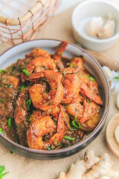 a bowl filled with cooked shrimp next to garlic and parsley on top of a table