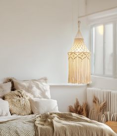 a bed with white sheets and pillows in a room next to a window, hanging from the ceiling