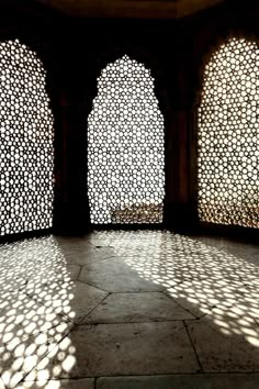 the sun shines through three arched windows in an ornately designed room with stone flooring