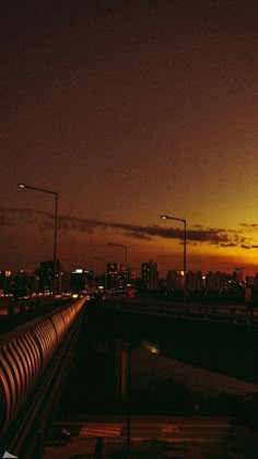 the city lights shine brightly in the distance as traffic passes by on an overpass