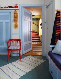 a room with blue walls and striped rugs on the floor next to a red chair