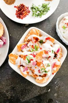 three plates filled with different types of food on top of a black countertop next to other dishes